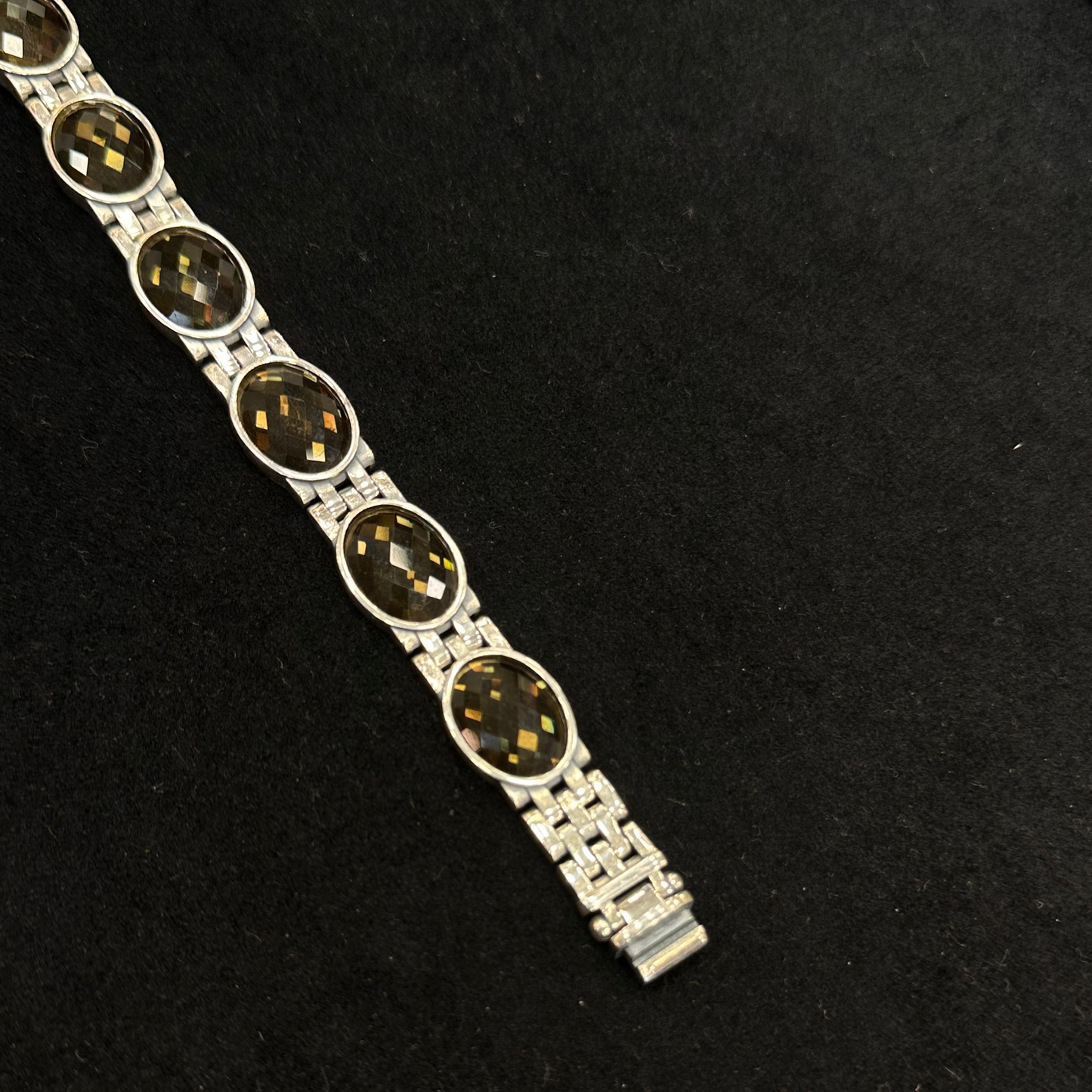 Silver bracelet with dark stones on a black background