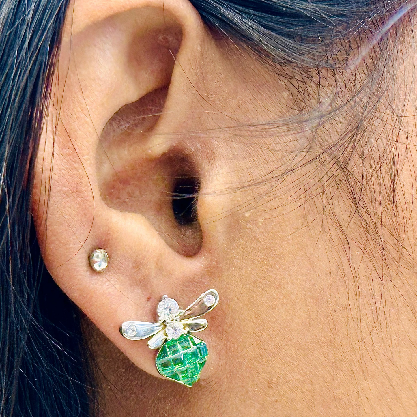 Close-up of an ear wearing a green and silver earring.