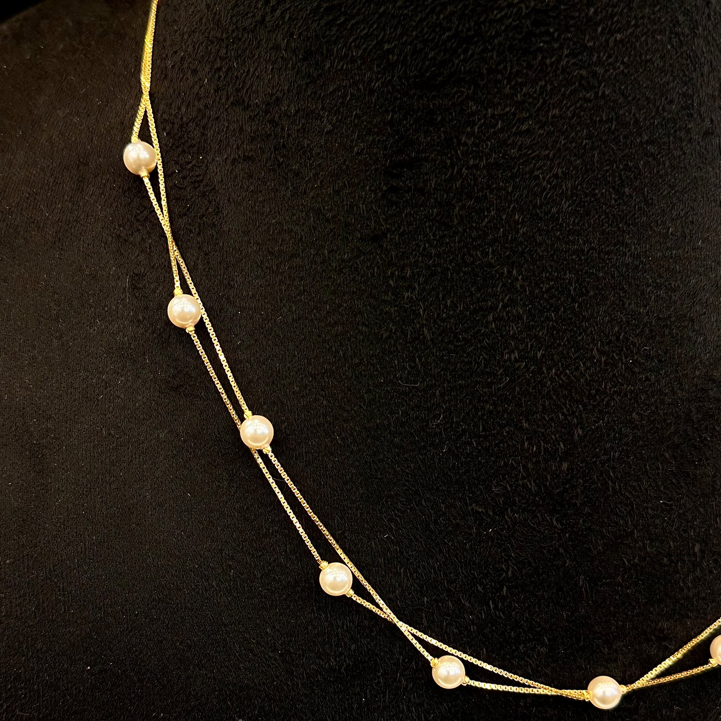 Gold necklace with pearls on a black background