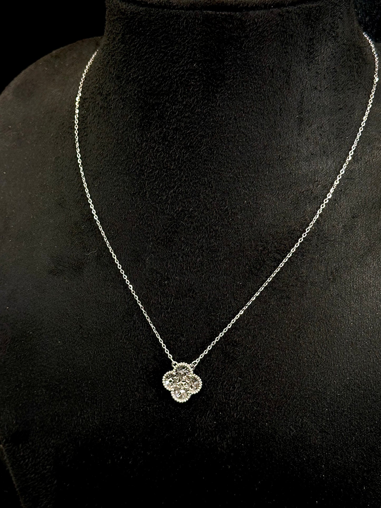 Necklace with a clover-shaped pendant on a black velvet stand