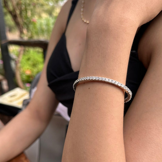 Close-up of a person's arm wearing a silver bracelet with a blurred outdoor background