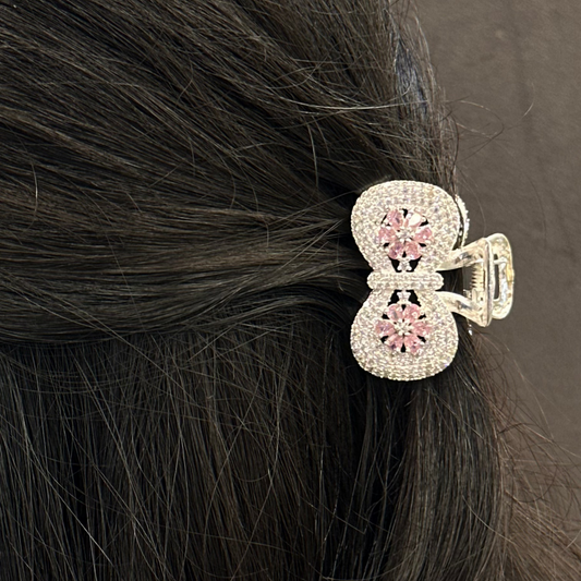 Hair clip with pink gemstones on dark hair against a brown background