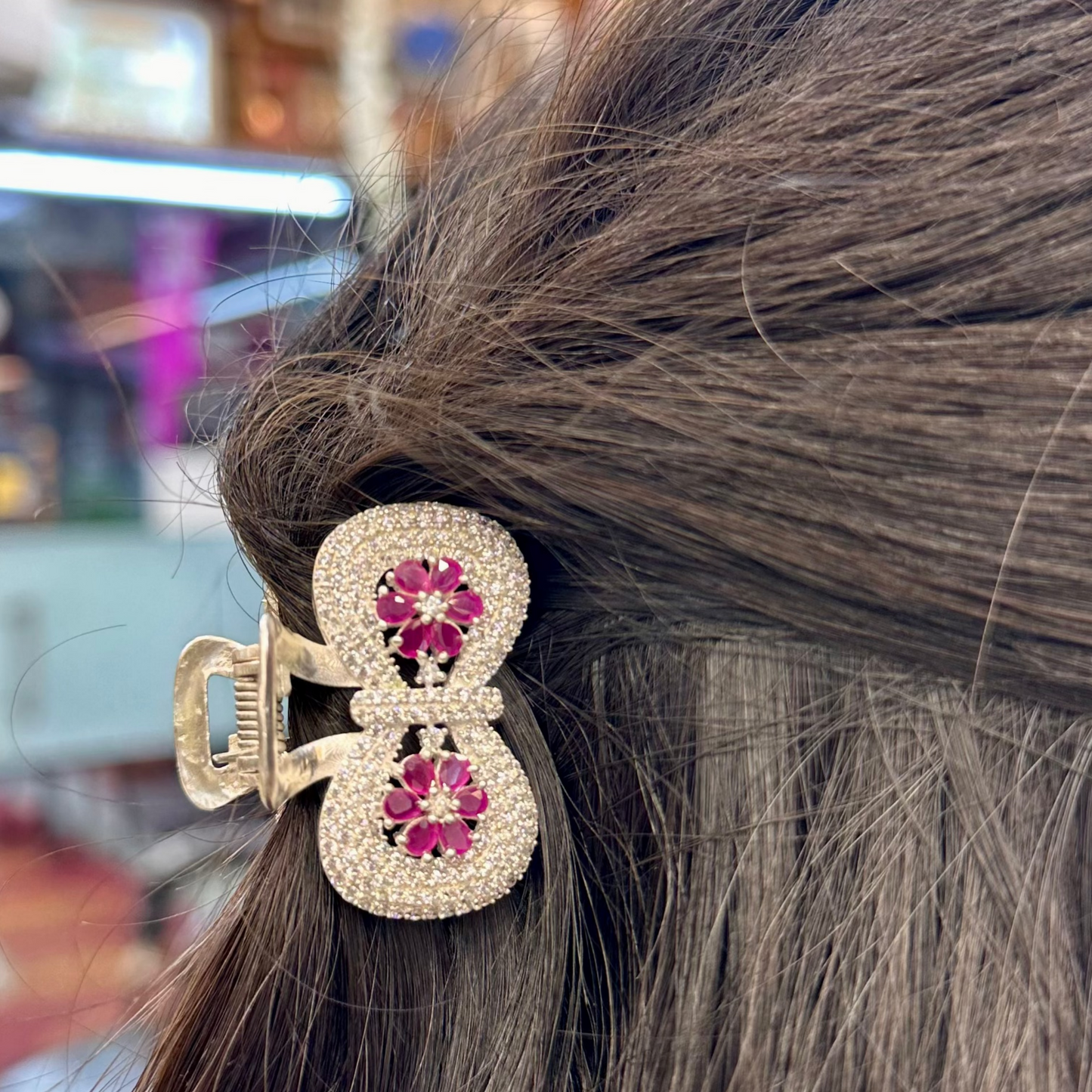 Hair clip with pink gemstones in a blurred indoor setting