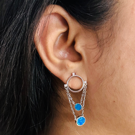 A close-up image of a woman's ear wearing a silver 925 Sterling Silver Azure Chain Cascade Earrings
earrings with blue opal stones attached to them.