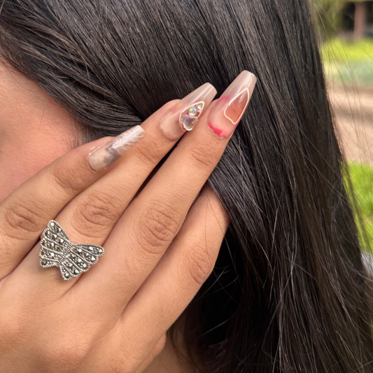 Woman with butterfly ring on finger holding hair outdoors