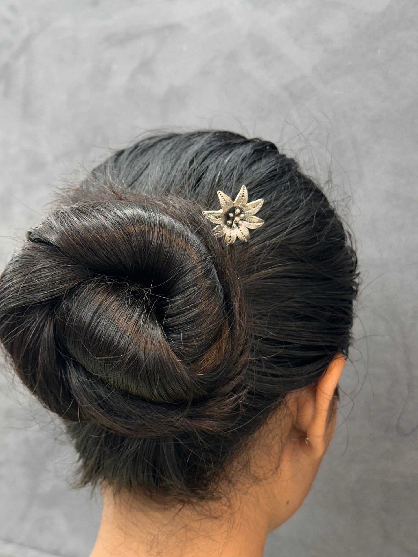 Updo hairstyle with a decorative hairpin on a neutral background
