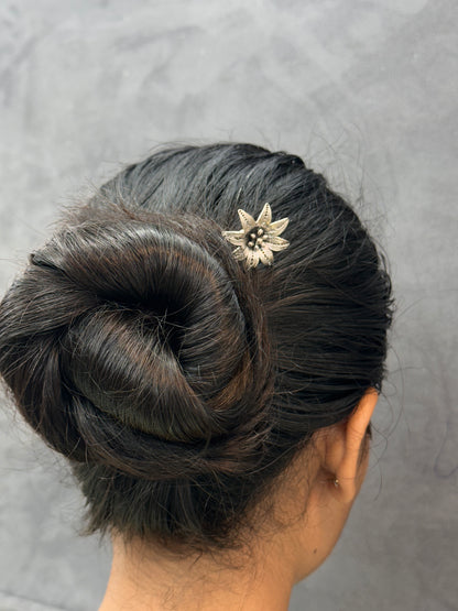 Updo hairstyle with a decorative hairpin on a neutral background