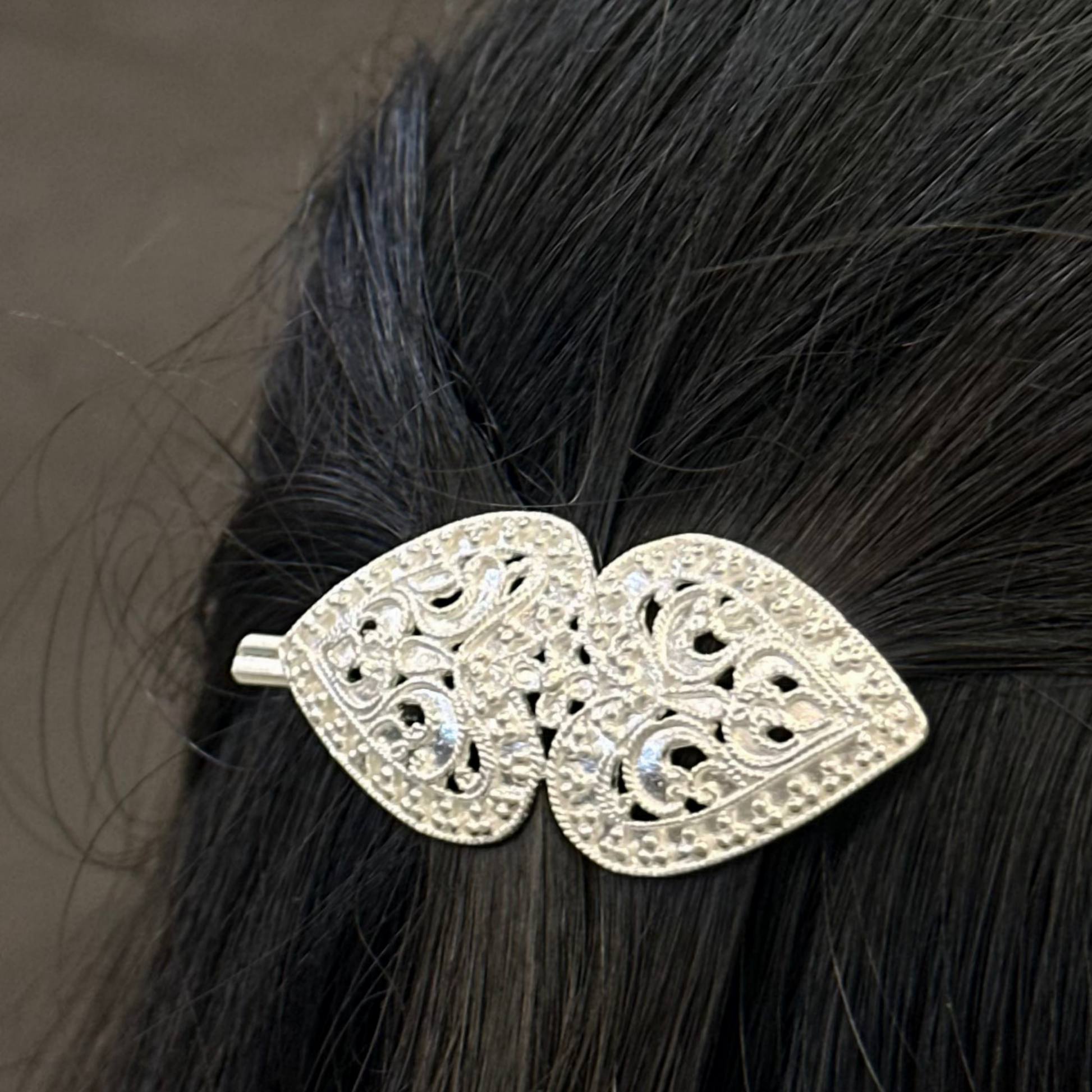 hair clip with leaf design on black hair against a brown background