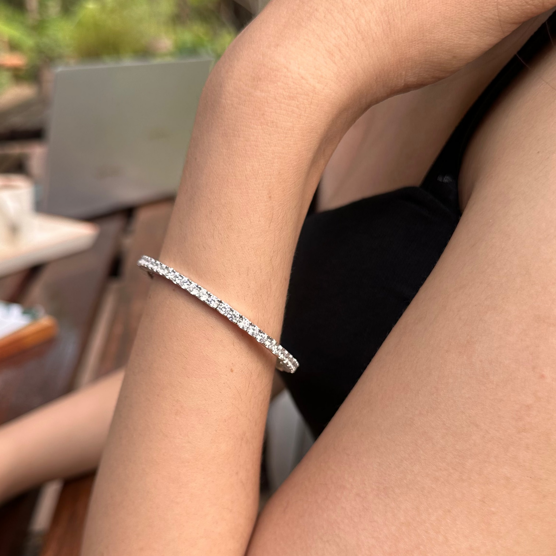 Person wearing a silver bracelet with a blurred outdoor background