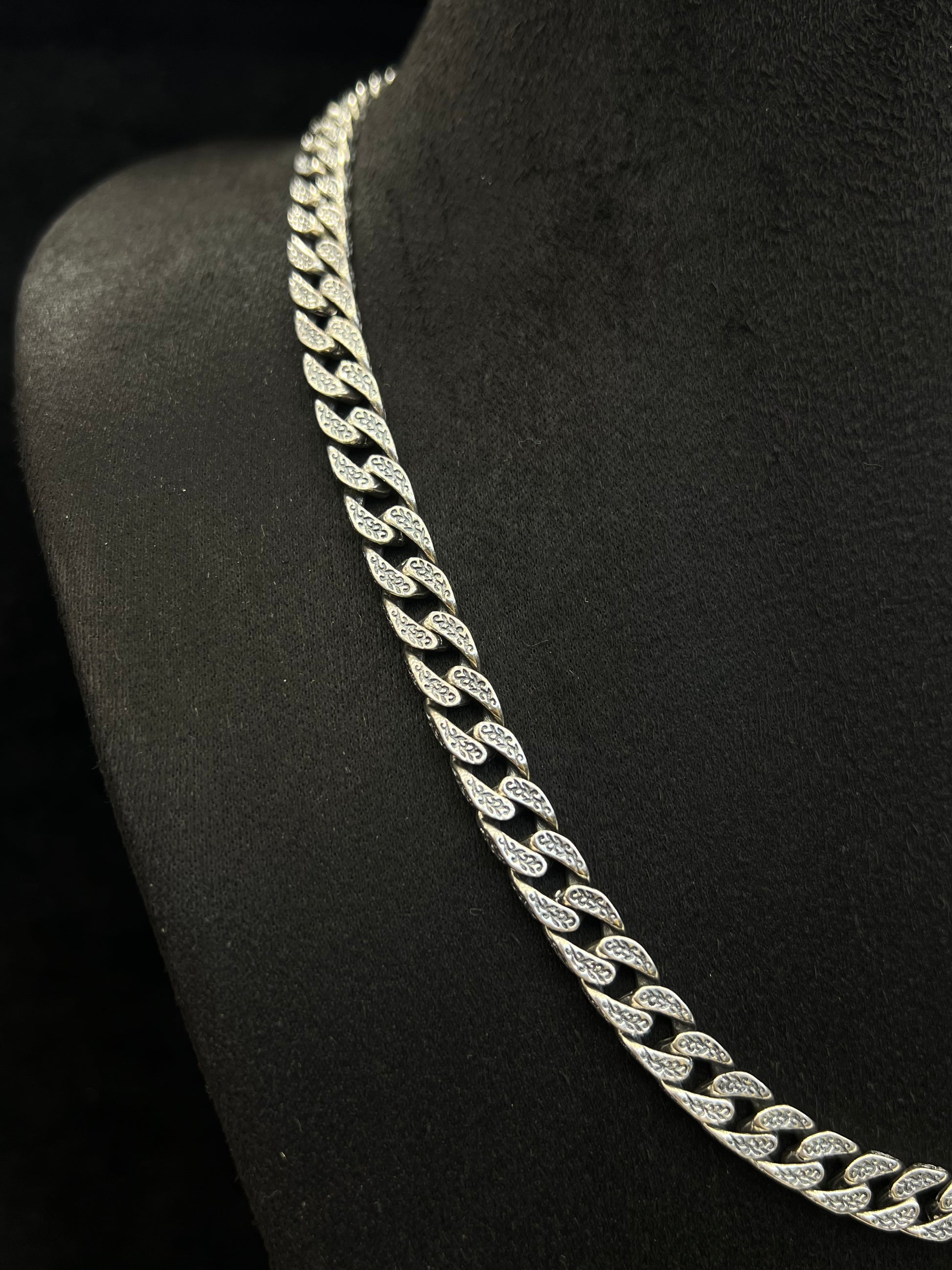 Silver chain necklace on a black stand