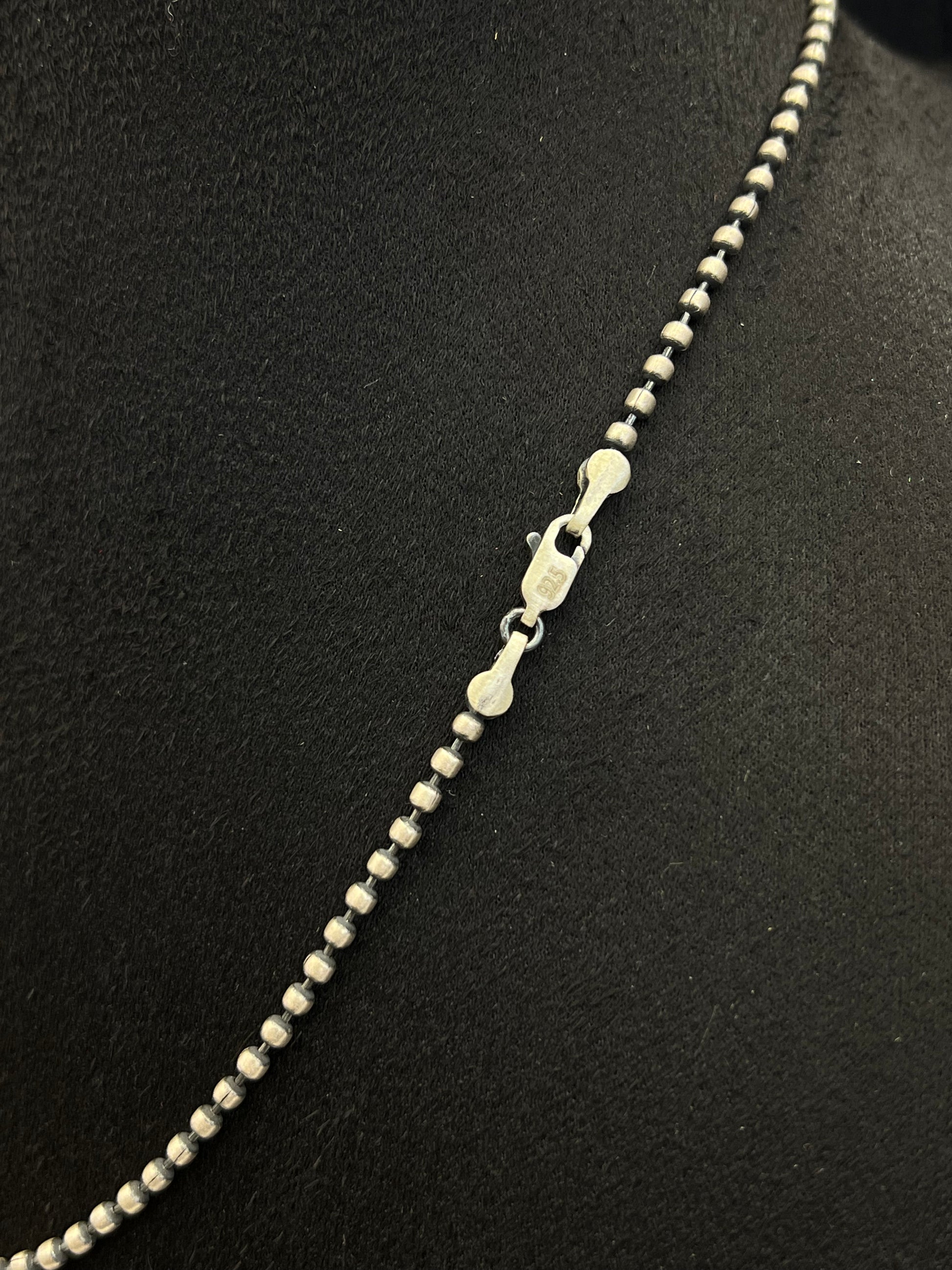 Silver beaded necklace on a black background