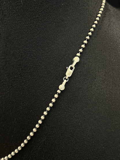 Silver beaded necklace on a black background