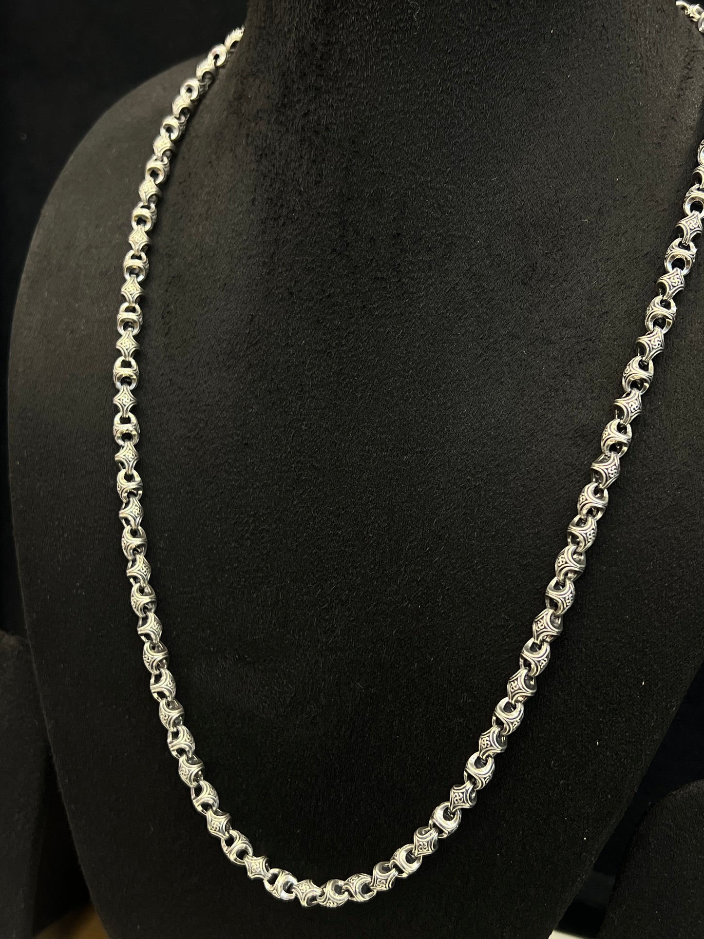 Silver chain necklace on a black mannequin