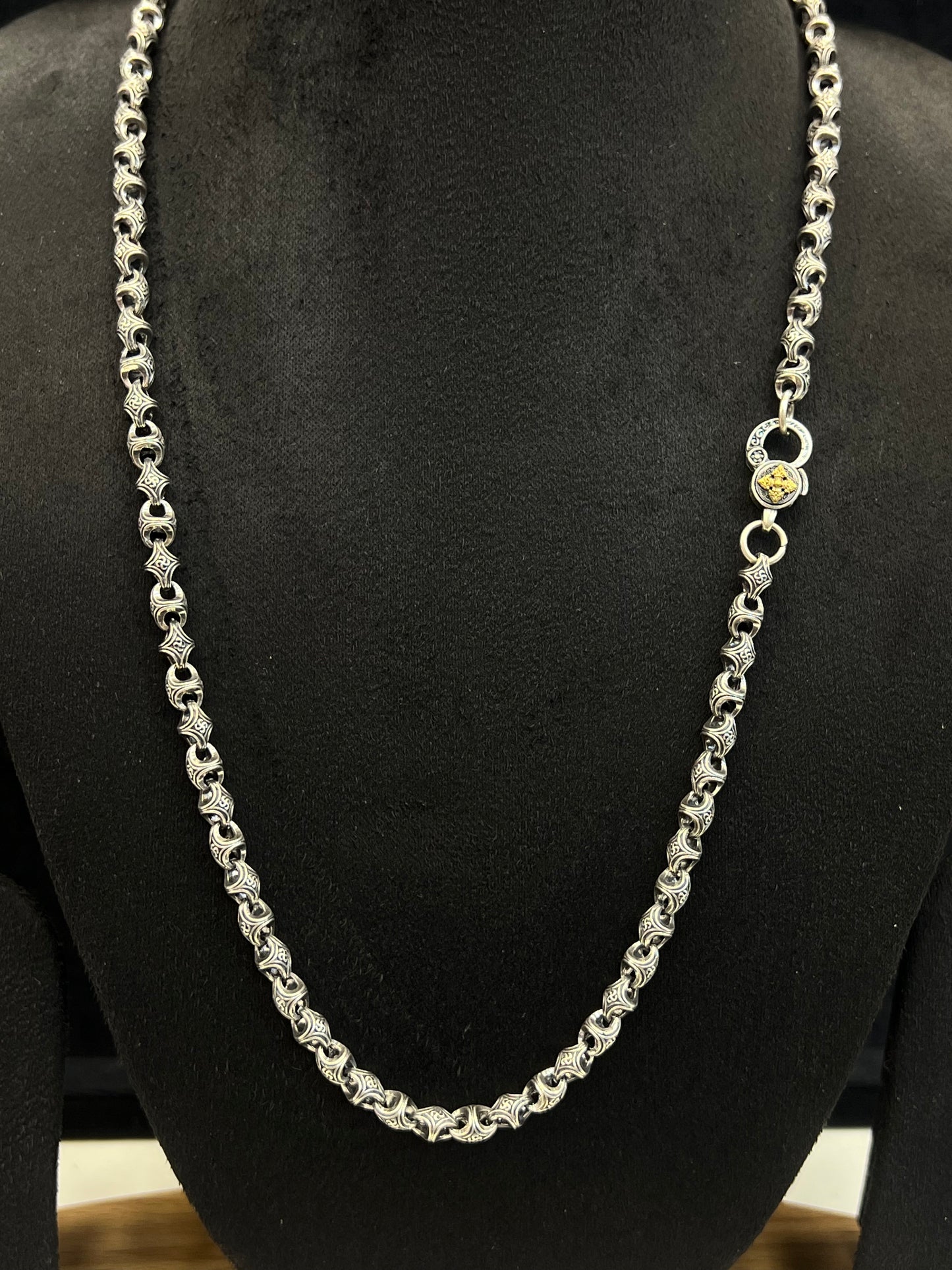 Silver chain necklace on a black mannequin