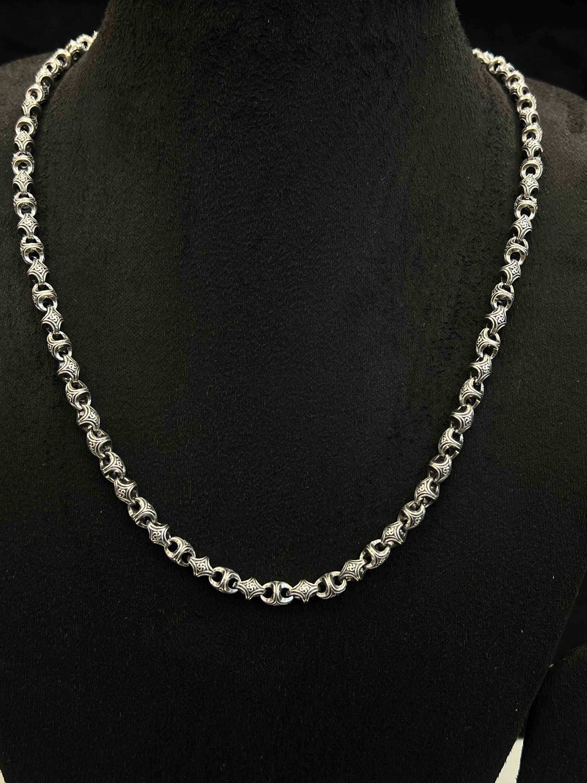 Silver chain necklace on a black mannequin