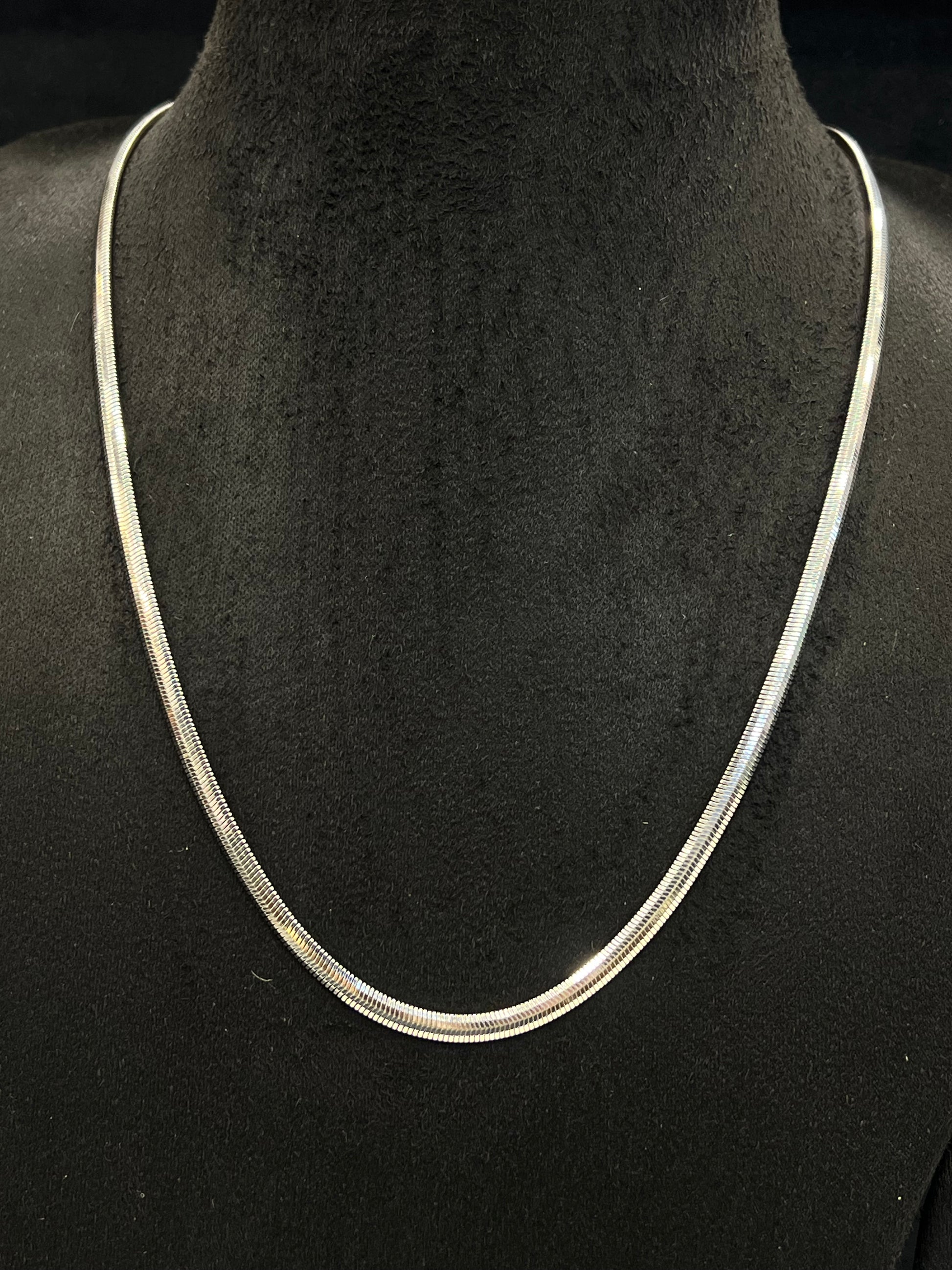 Silver necklace on a black mannequin