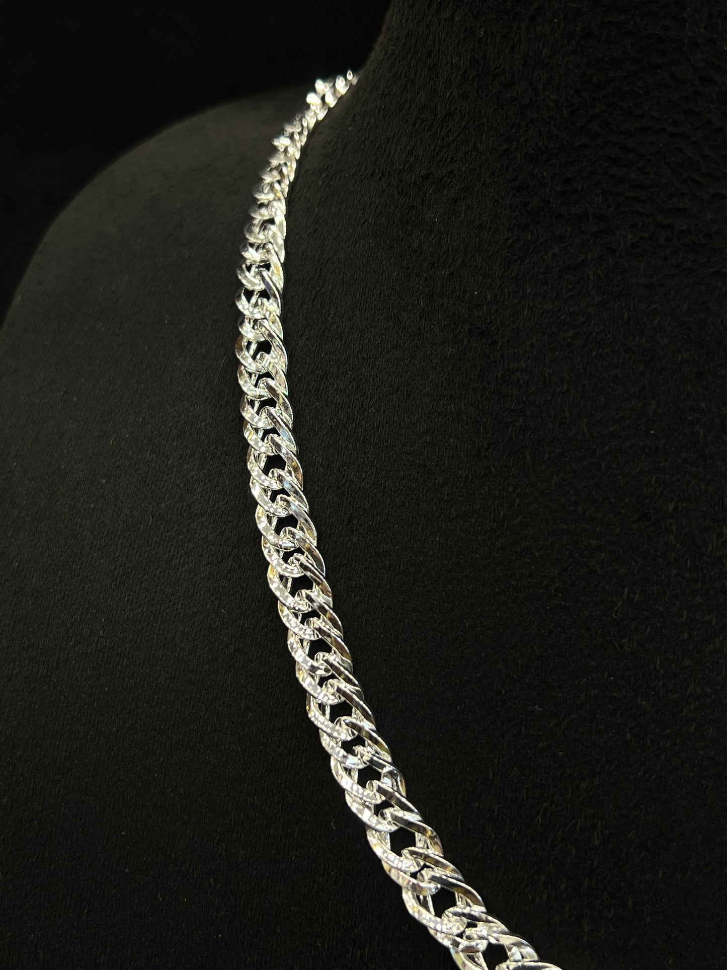 Silver chain necklace on a black mannequin