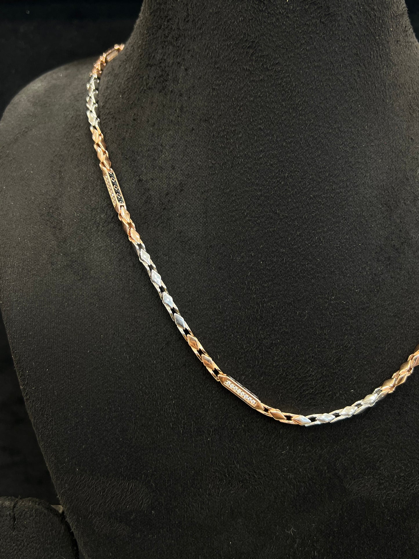 Gold and silver chain on a black mannequin bust
