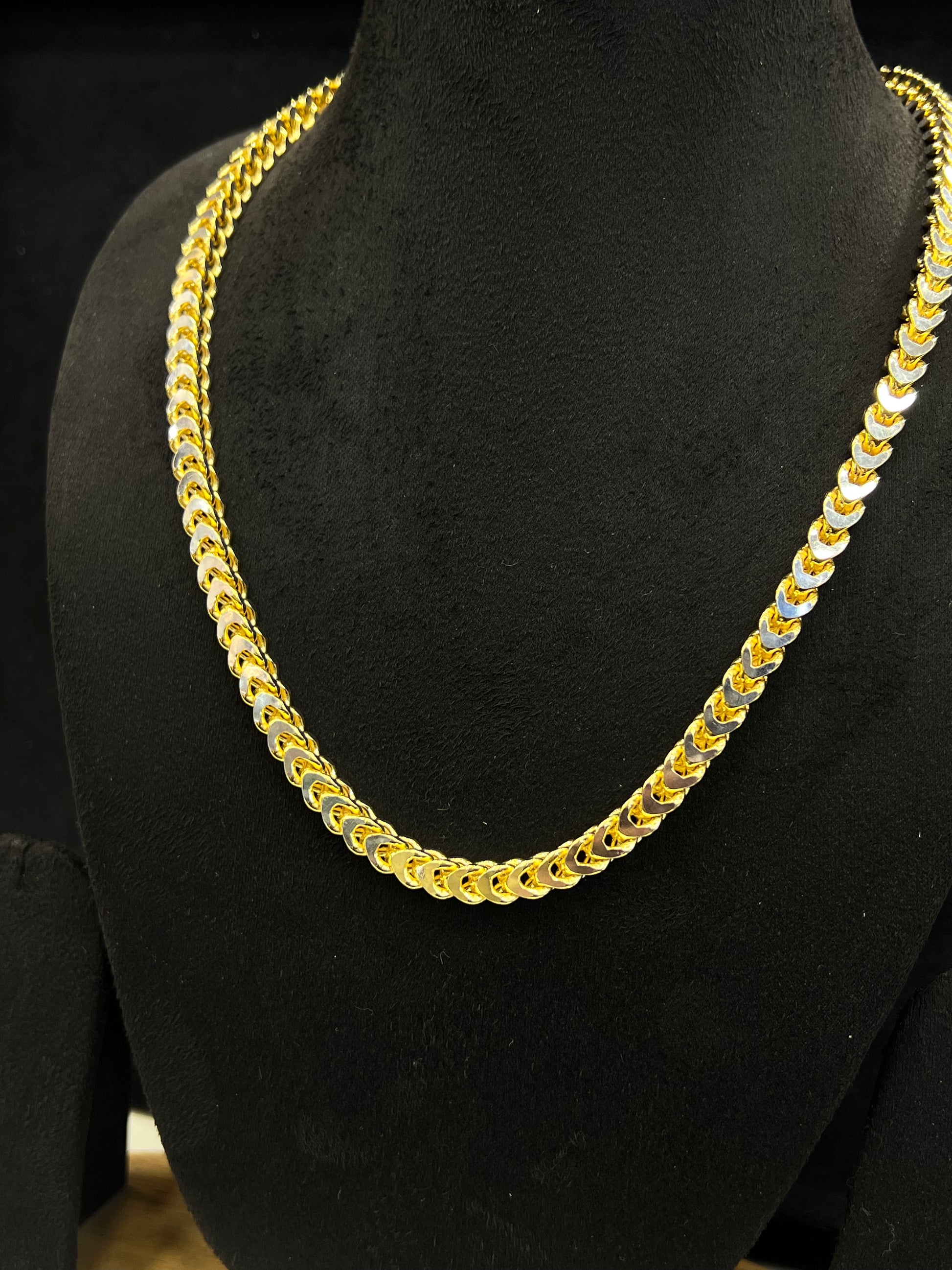 Gold chain necklace on a black mannequin