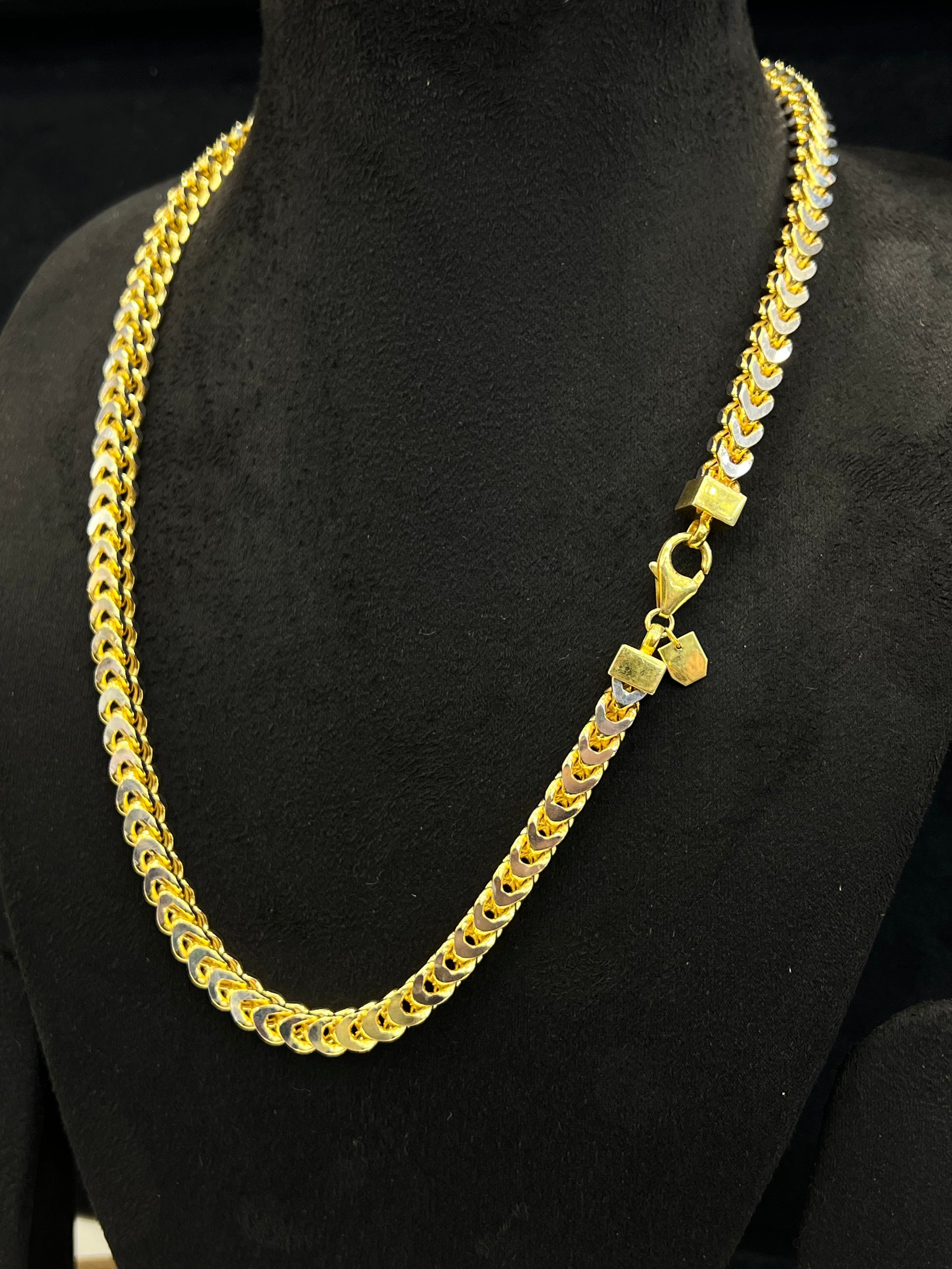 Gold chain necklace on a black mannequin
