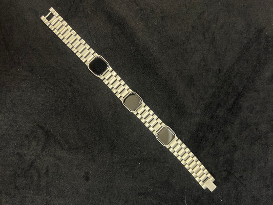 Metallic bracelet with a black square charm on a dark textured background