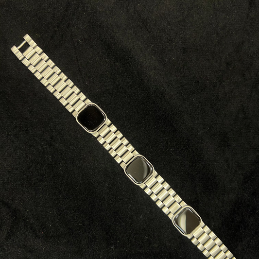 Metallic bracelet with a black square charm on a dark textured background