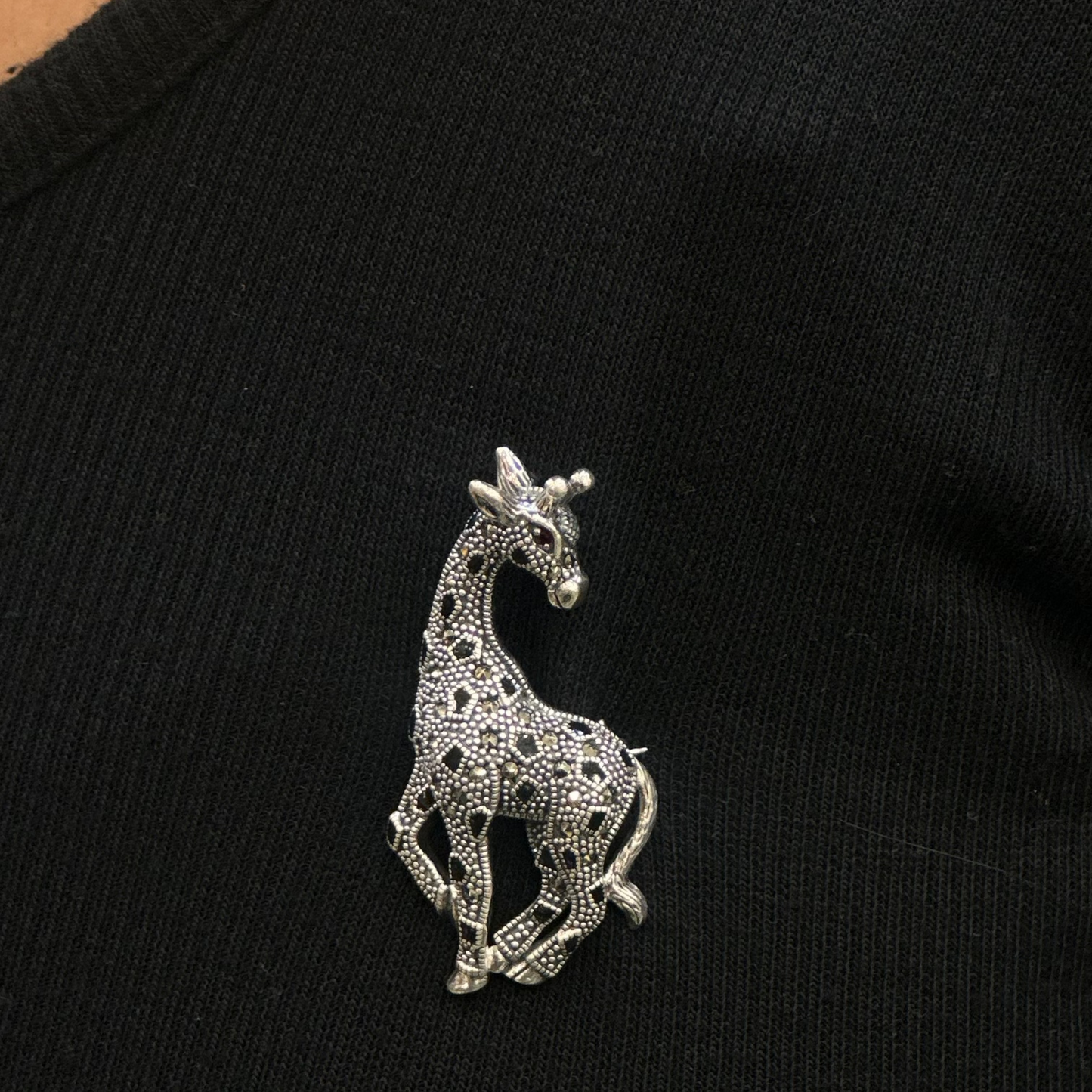 Silver giraffe brooch on a black garment