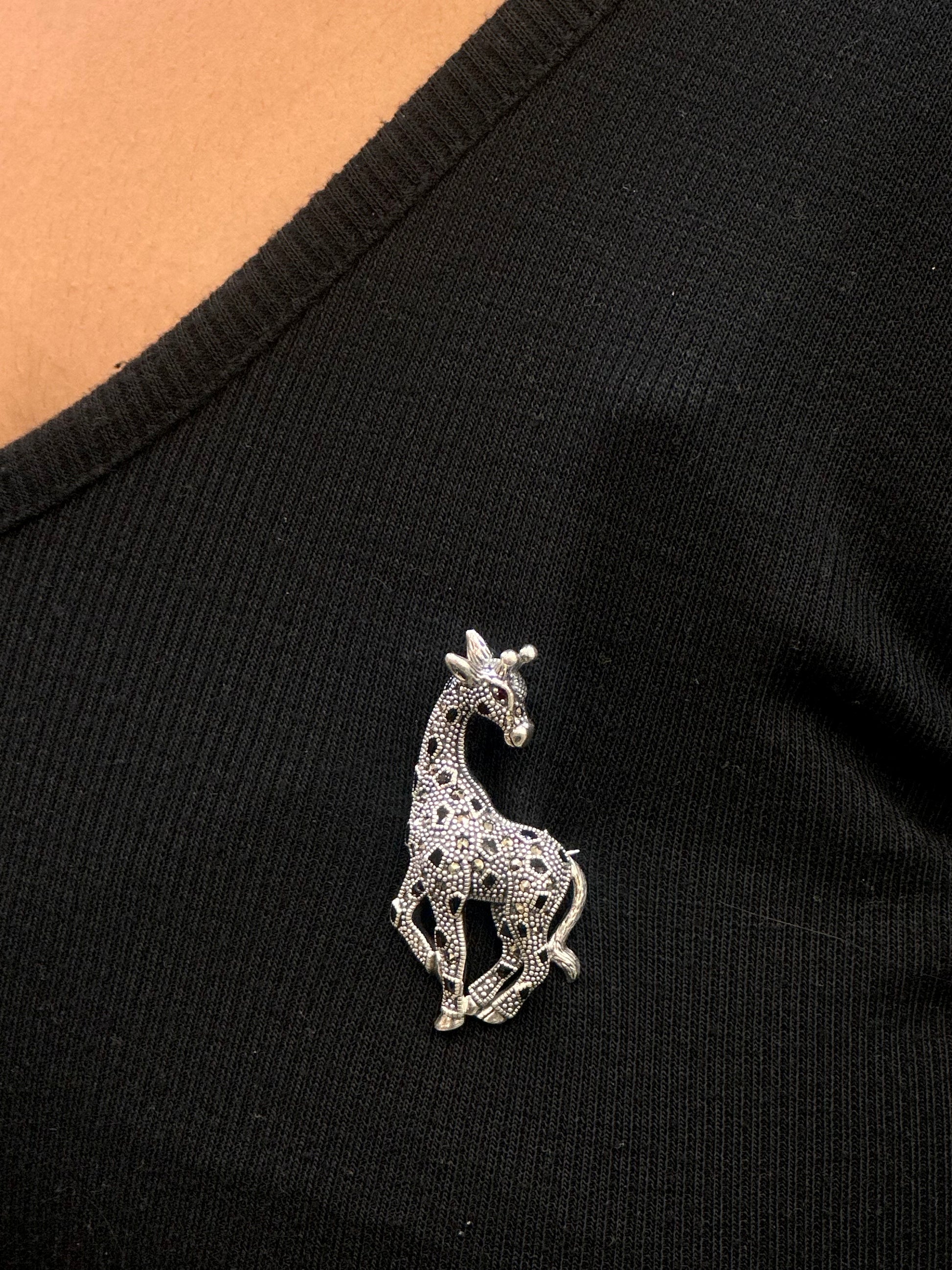 Silver giraffe brooch on a black garment