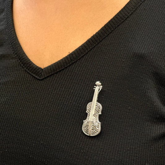 Silver violin-shaped brooch on a black shirt