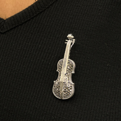 Silver violin-shaped brooch on a black shirt