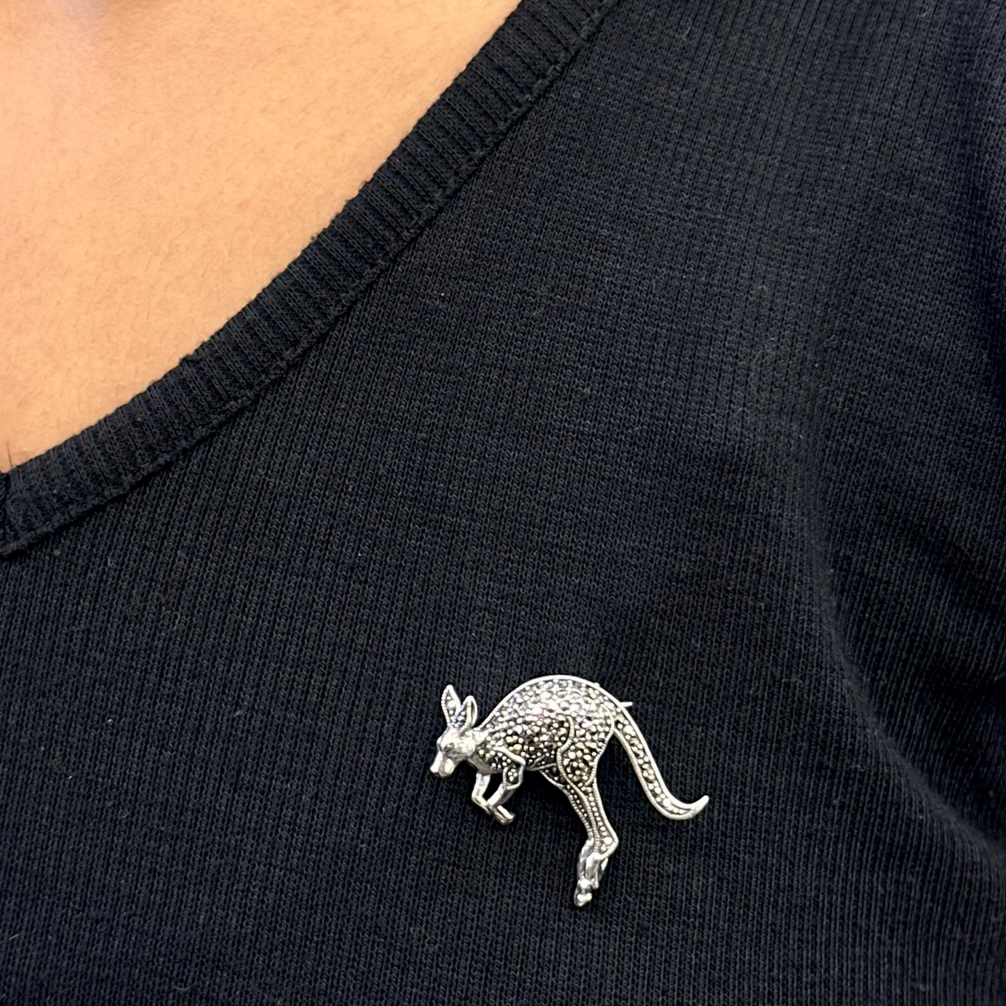 Black shirt with a silver kangaroo brooch worn by a person