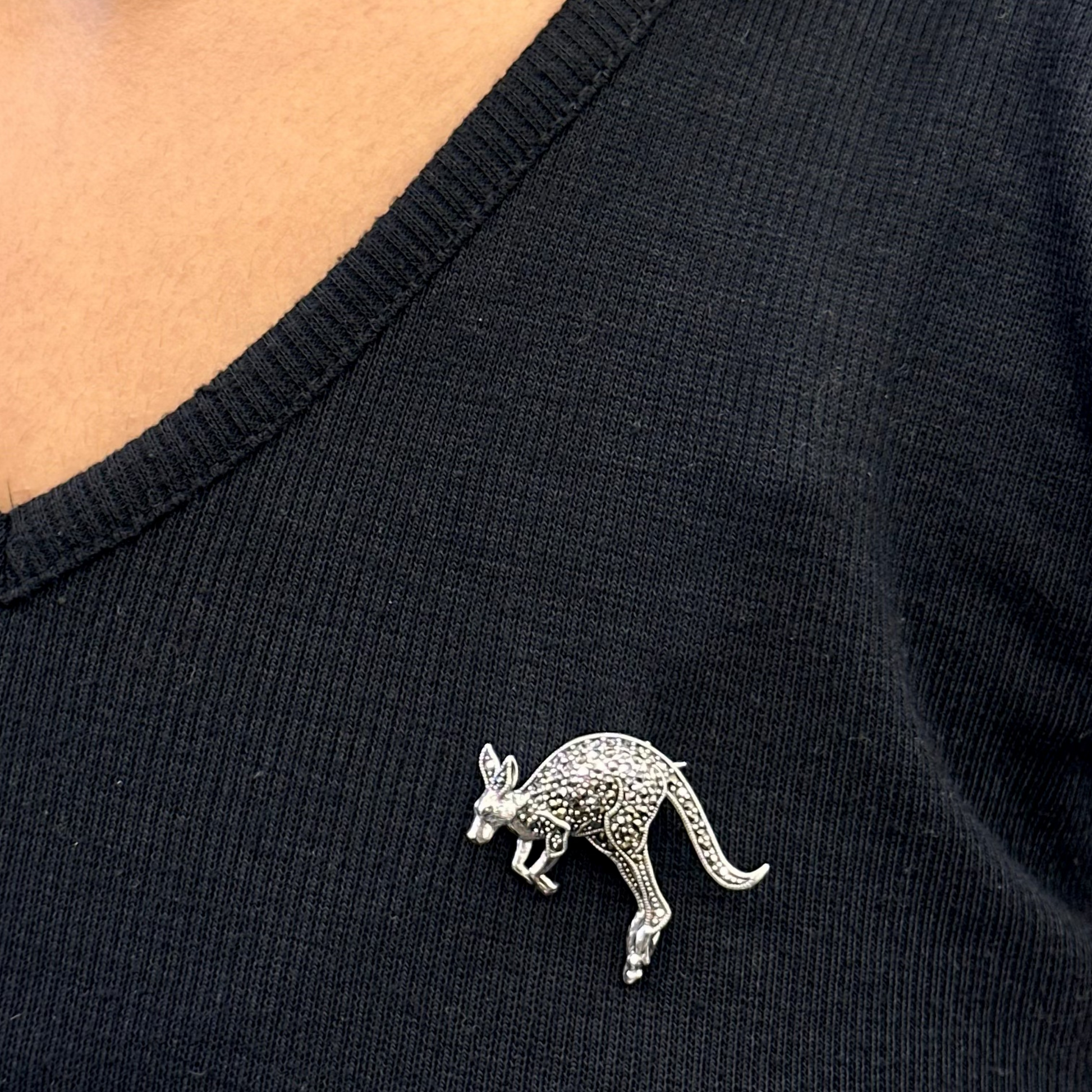 Black shirt with a silver kangaroo brooch worn by a person