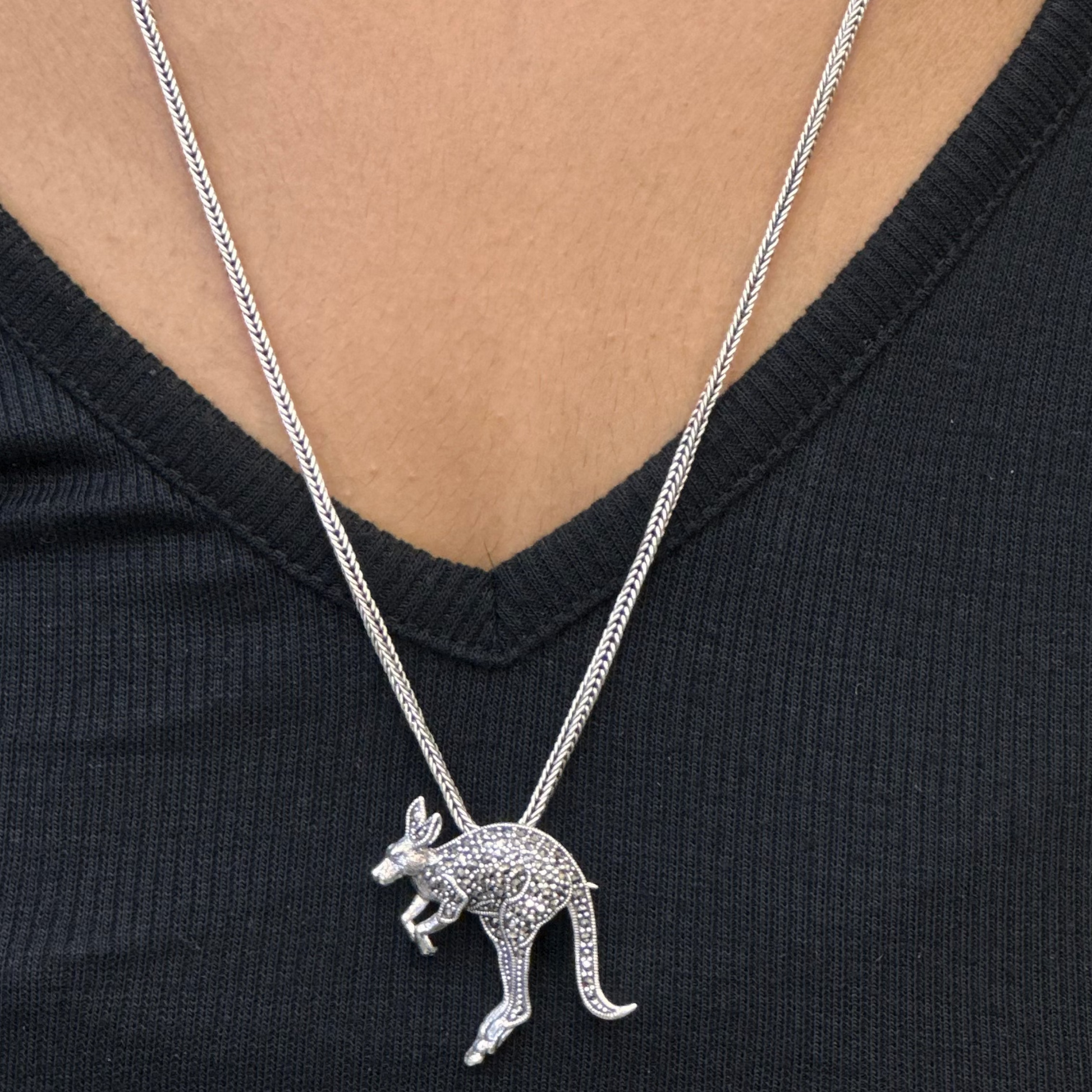 Silver kangaroo pendant necklace on a person wearing a black top
