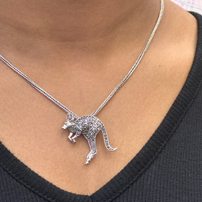 Silver kangaroo pendant necklace on a person wearing a black top.