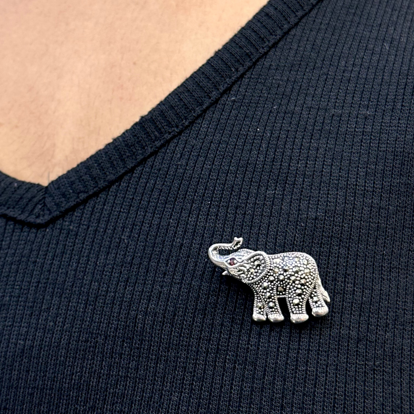 Silver elephant brooch on a dark blue shirt