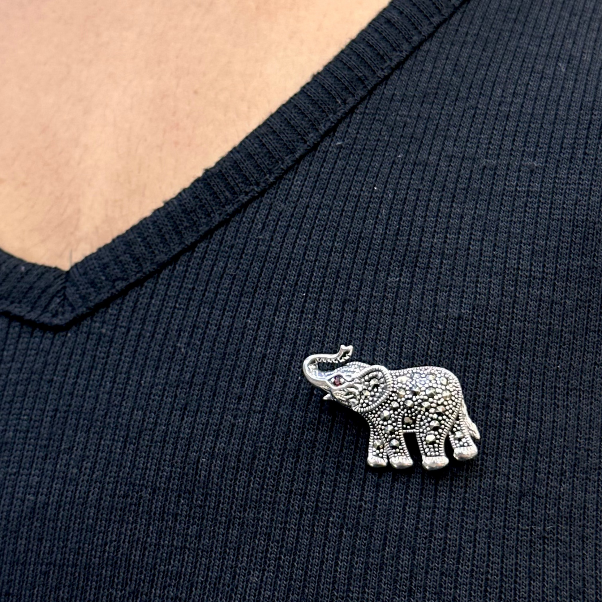 Silver elephant brooch on a dark blue shirt