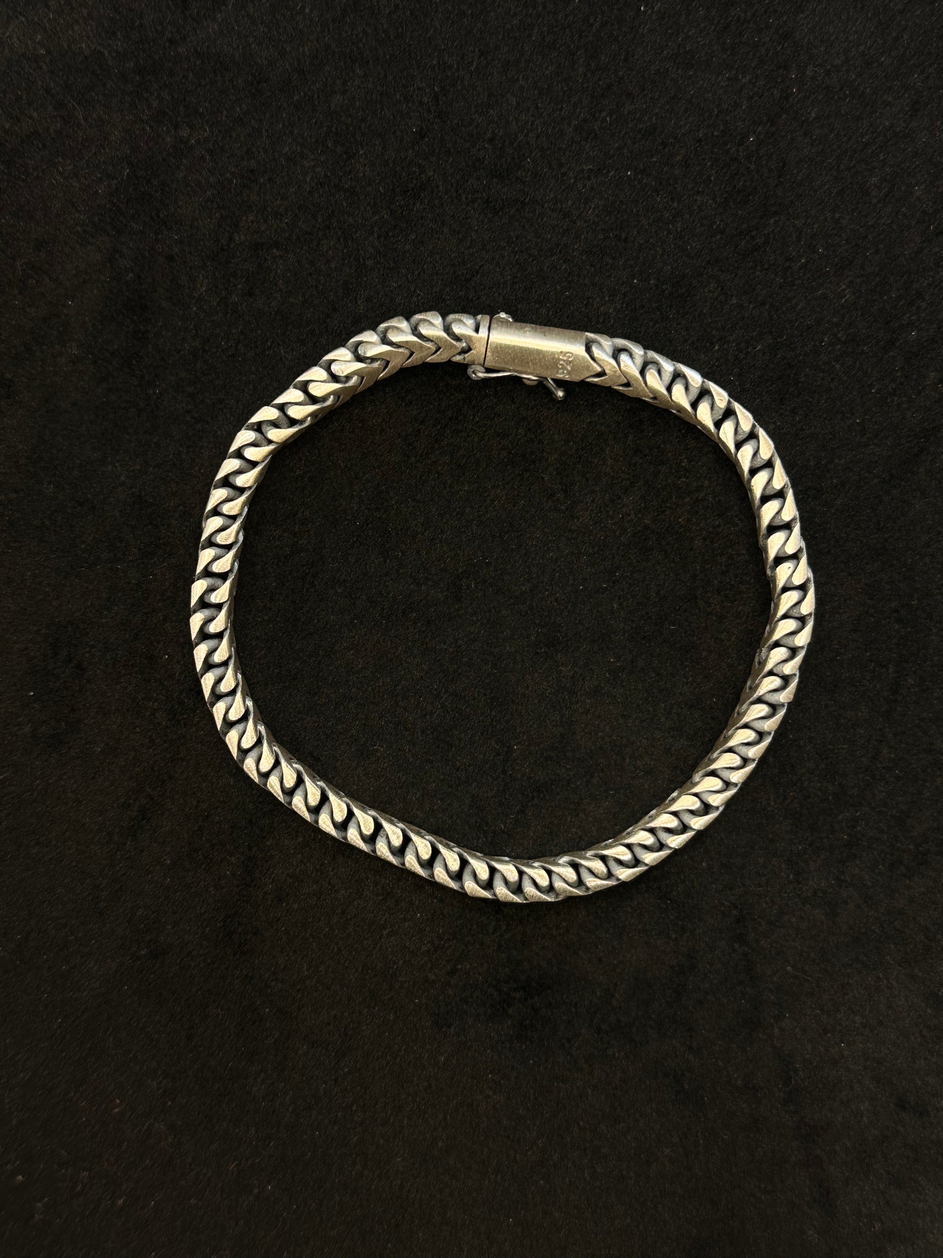 Silver bracelet with braided design on a black background