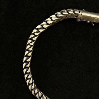 Silver bracelet with braided design on a black background