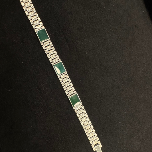 Silver bracelet with green stones on a black background