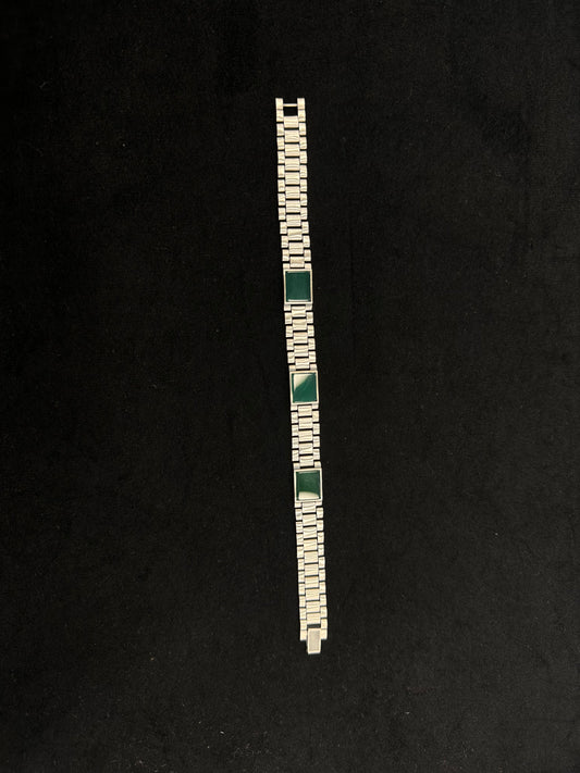 Silver bracelet with green stones on a black background