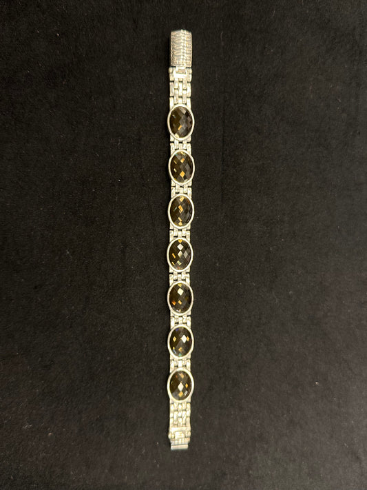 Silver bracelet with dark stones on a black background