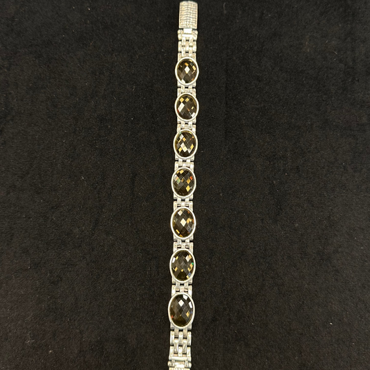 Silver bracelet with dark gemstones on a black background