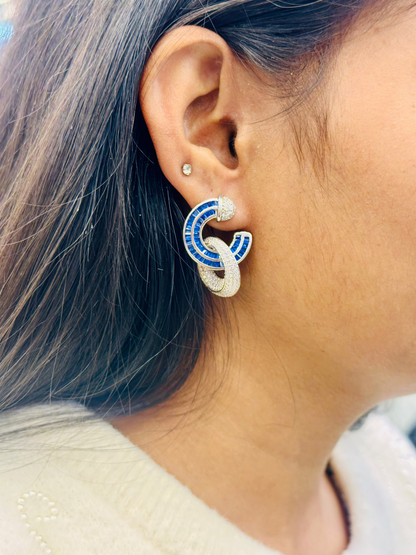 Close-up of an ear wearing a unique earring with blue and white design.