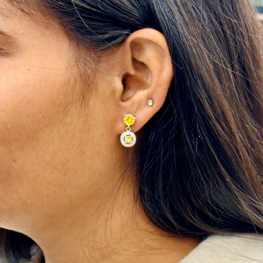 Close-up of a person wearing a yellow and clear gemstone earring.
