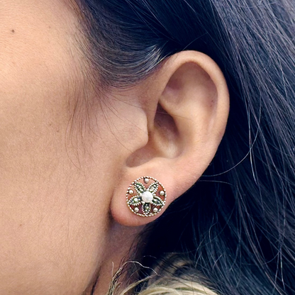 Close-up of an ear wearing a decorative earring with hair partially obscuring the view.