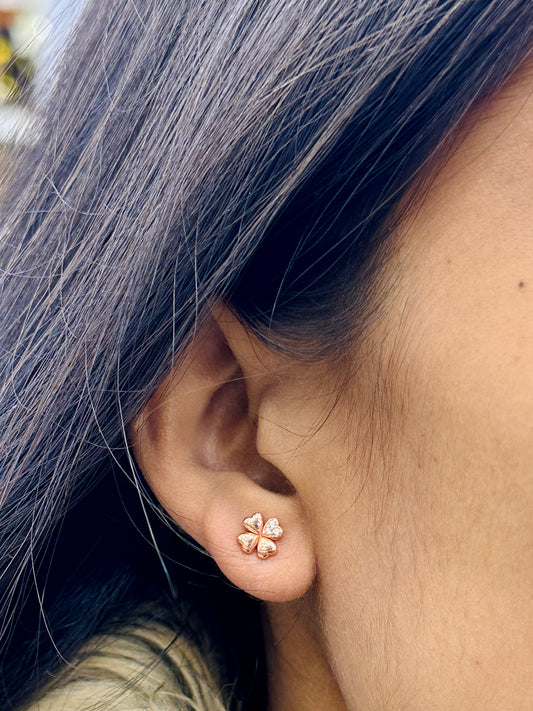 Close-up of an ear wearing a floral earring with dark hair.