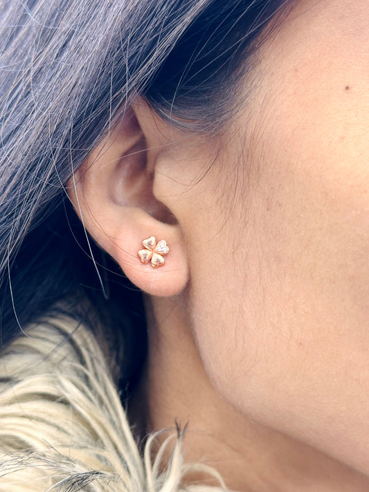 Close-up of a person wearing a gold four-leaf clover earring.