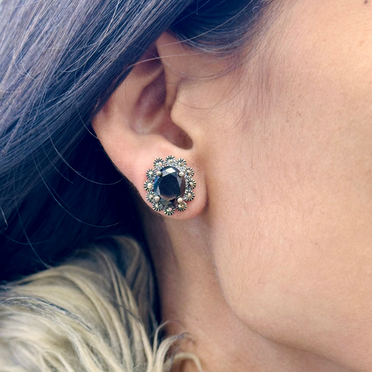Close-up of a person wearing a decorative earring with a dark gemstone.