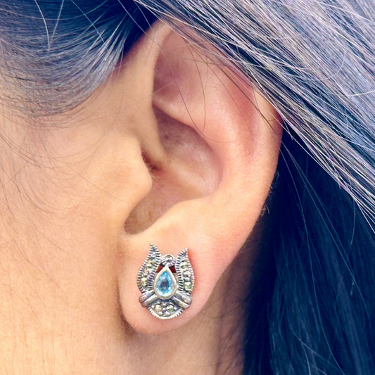 Close-up of an ear wearing a decorative earring with hair partially covering it.