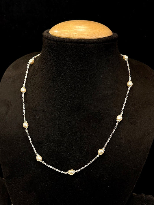 Pearl necklace on a black mannequin with a wooden base against a black background